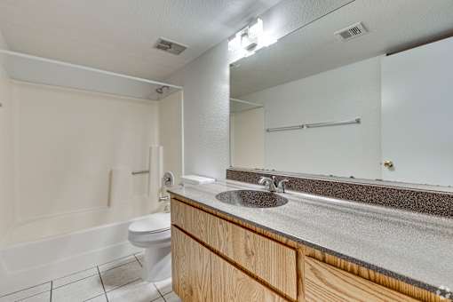 A bathroom with a white toilet, sink, and a mirror.
