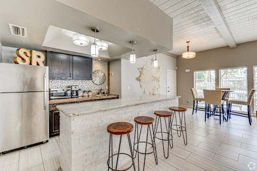 A kitchen with a white refrigerator and bar stools.