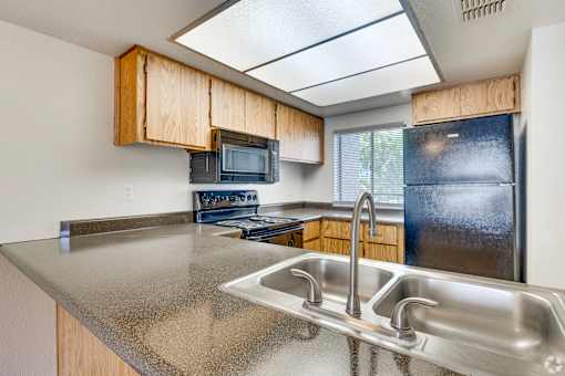 A kitchen with a stainless steel sink and wooden cabinets.
