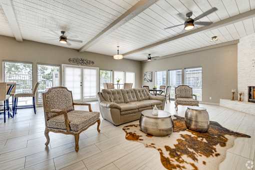 A living room with a wooden chair, a grey sofa, and a cowhide rug.