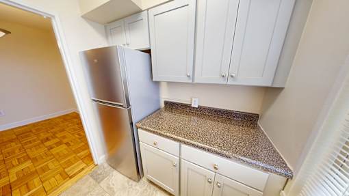 A kitchen with a refrigerator, cabinets, and a countertop.