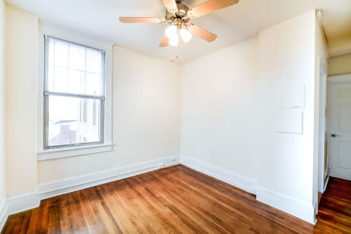 vacant living area with large windows, ceiling fan and hardwood flooring at the cortland apartments in washington dc