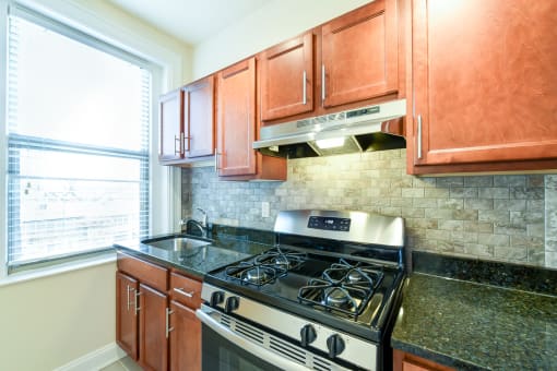 kitchen with stainless steel appliances, wood cabinetry and large window at  2701 Connecticut apartments in washington dc