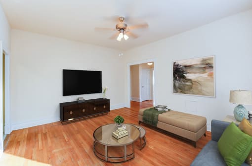 living area with sofa, coffee table, credenza, tv, hardwood floors and ceiling fan at chatham courts apartments in washington dc