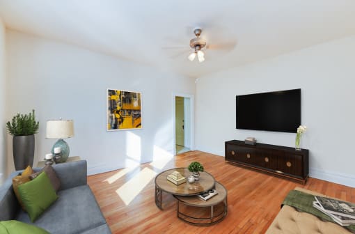 living area with sofa, coffee table, credenza, tv, hardwood floors and ceiling fan at chatham courts apartments in washington dc