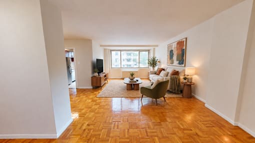 A living room with a brown wooden floor and a large window.