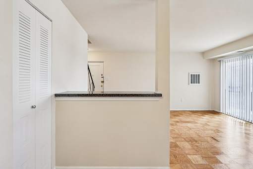 A kitchen with a white counter and wooden floor.