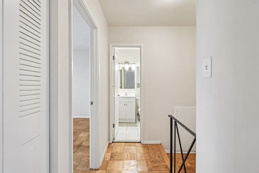 A white door is open to a room with a wooden floor.