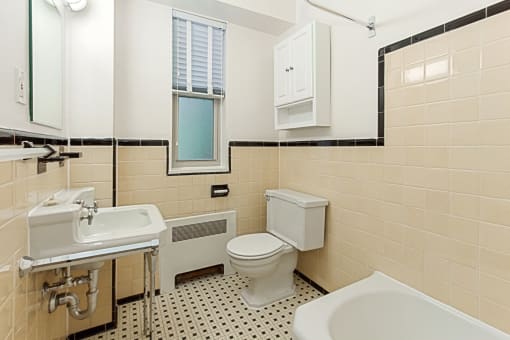 bathroom with toilet, tub, sink, window and large mirror at 2800 woodley road apartments in washington dc