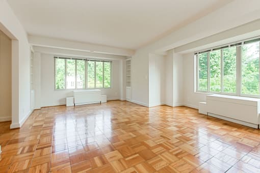 vacant living area with hardwood flooring and large windows at 2800 woodley road apartments in northwest washington dc