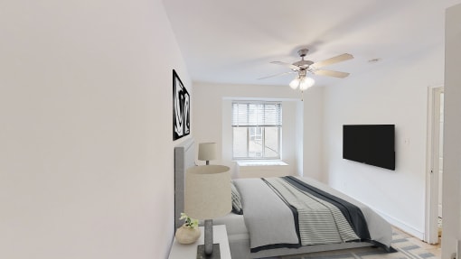 bedroom with bed, nightstands, large window and ceiling fan at 2800 woodley apartments in washington dc