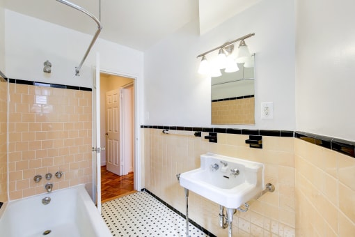 bathroom with tub, sink, mirror and tile details at 2800 woodley road apartments in woodley park washington dc