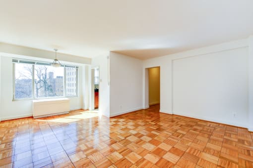 vacant living area with hardwood flooring and large window at 2800 woodley road apartments in woodley park washington dc
