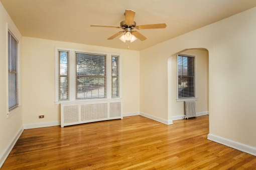 vacant living area with hardwood floors, large windows and ceiling fan at 2801 pennsylvania apartments in washington dc