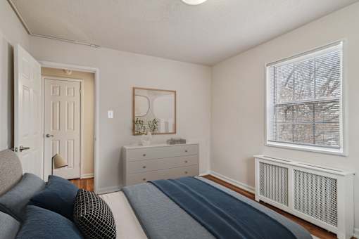 A bedroom with a bed, nightstand, and window.