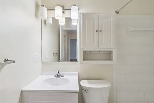 A white bathroom with a sink, toilet and cabinet.
