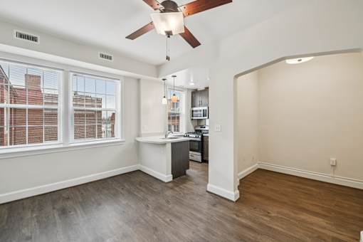 A room with a ceiling fan and a desk with a computer.