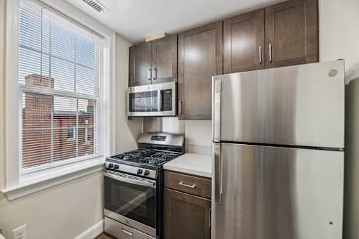 A kitchen with a stainless steel refrigerator, microwave, oven, and stove.