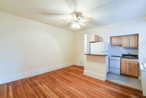 vacant living area with hardwood flooring, ceiling fan and view of kitchen at the cortland apartments in washington dc