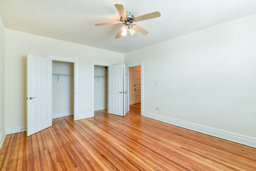 vacant bedroom with ceiling fan, hardwood floors, and large closets at 2701 connecticut ave apartments in washington dc
