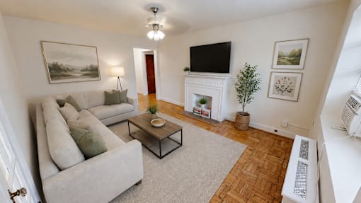 A living room with a grey couch, a coffee table, a fireplace, and a painting on the wall.