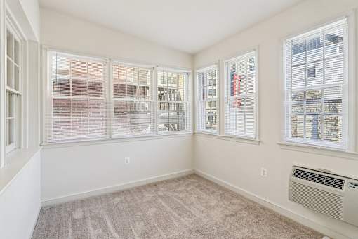 A room with a carpeted floor and a window with blinds.