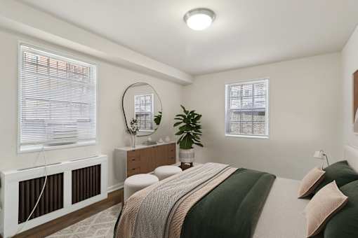 A bedroom with a bed, nightstand, and window with blinds.