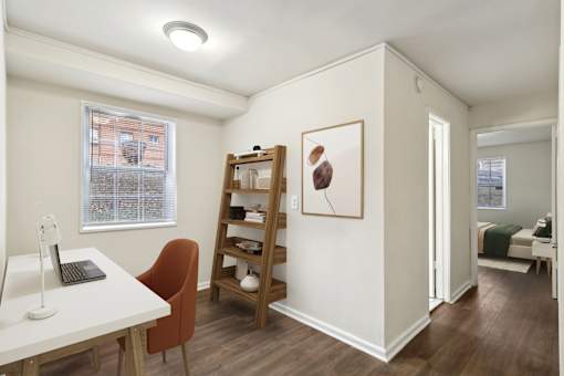 A room with a desk, chair, and a painting on the wall.