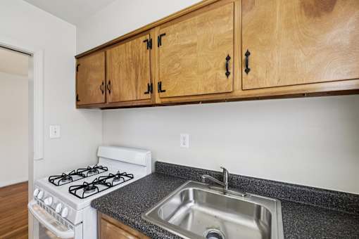 A kitchen with a white stove and wooden cabinets.