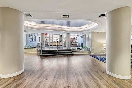 A spacious room with wooden floors and white columns.