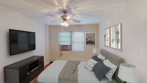 bedroom with bed, nightstands, dresser, tv, ceiling fans and large windows at alpha house apartments in washington dc