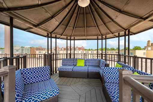 A patio with a blue and white patterned couch and a wooden table.