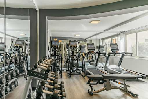 A gym with a variety of equipment including treadmills, weights, and exercise machines.