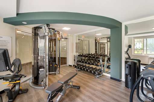 A gym with a variety of equipment including treadmills, weights, and exercise machines.