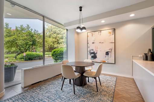 A dining room with a table and chairs and a large window.