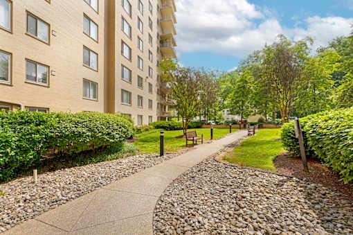 A cobblestone pathway leads through a grassy area in front of a building.