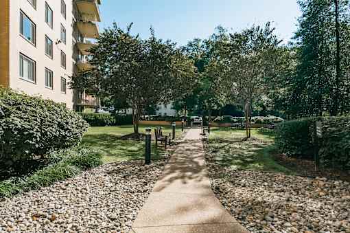 A walkway in a park with a building in the background.