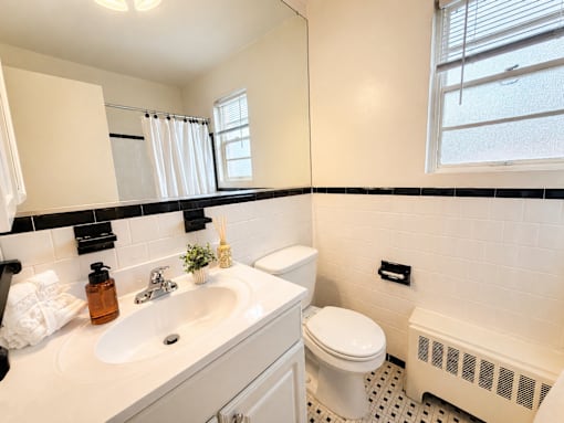 A white bathroom with a toilet, sink, and a window.