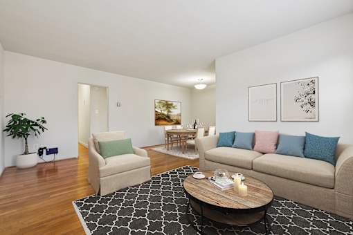 A living room with a beige couch, a coffee table, and a potted plant.