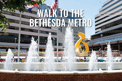 A fountain in front of a building with the text "Walk to the Bethesda Metro" overlaid on the image.