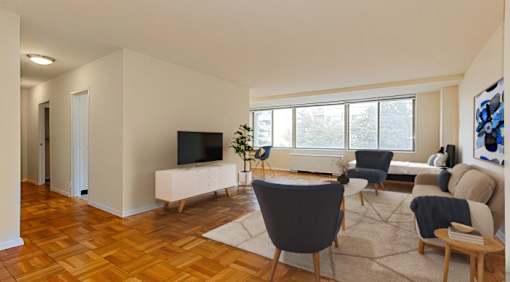 A living room with a television, chairs, and a rug.