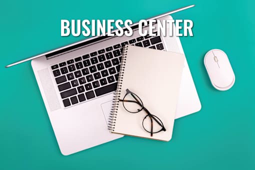 A business center setup with a laptop, mouse, and glasses on a notepad.
