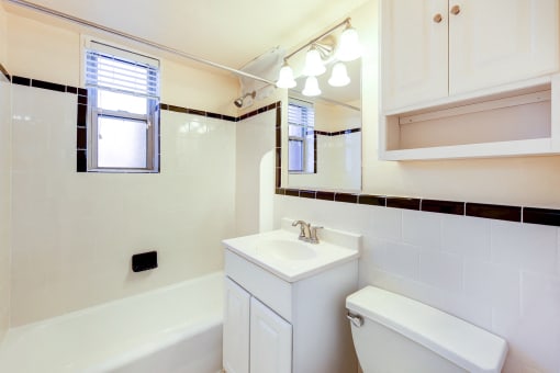 bath room with view of toilet, vanity, tub, and window at cambridge square apartments in bethesda md