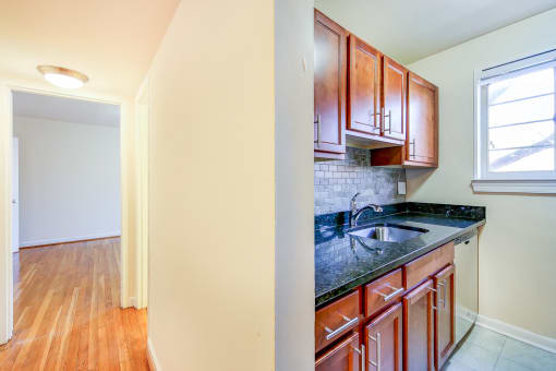 kitchen with wood cabinetry, tile backsplash, and window at cambridge square apartments in bethesda md