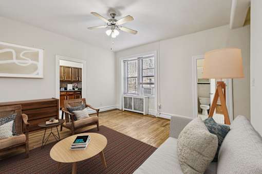 A living room with a couch, a chair, a coffee table, and a ceiling fan.