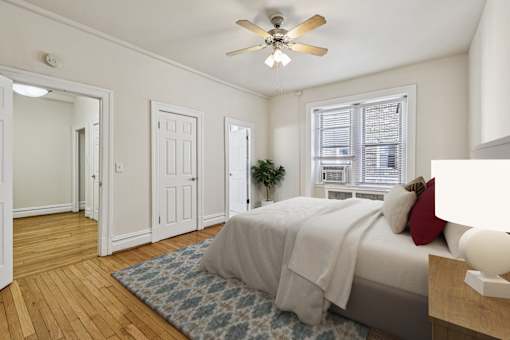 A bedroom with a bed, a ceiling fan, and a rug.