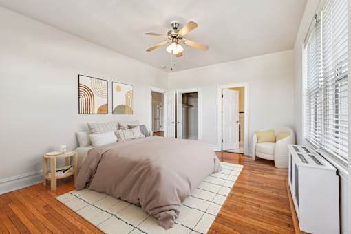 A bedroom with a bed, a chair, and a ceiling fan.