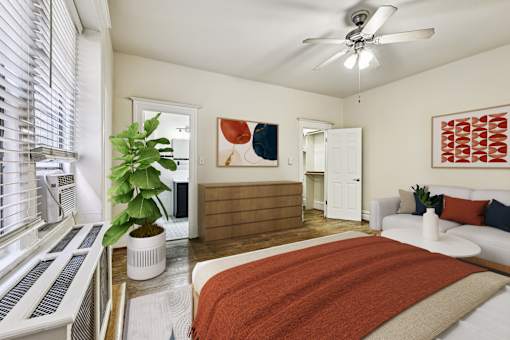 A bedroom with a bed, a plant, and a painting on the wall.