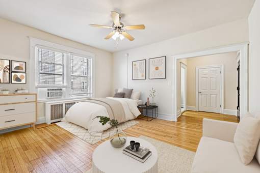 A bedroom with a bed, a dresser, a window, a ceiling fan, and a rug.