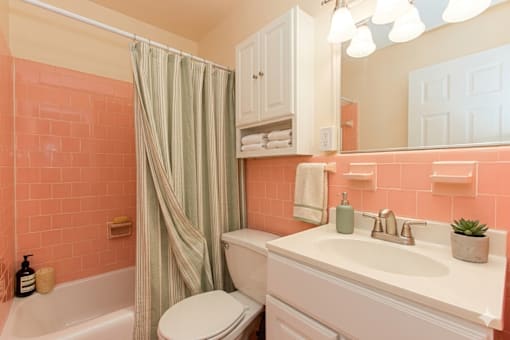A bathroom with a white toilet, a white sink, and a shower with a green curtain.